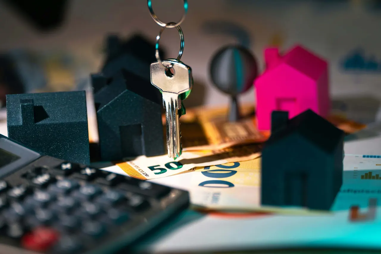 Wohnungsschlüssel, Hausmodelle, Geldscheine und Taschenrechner
